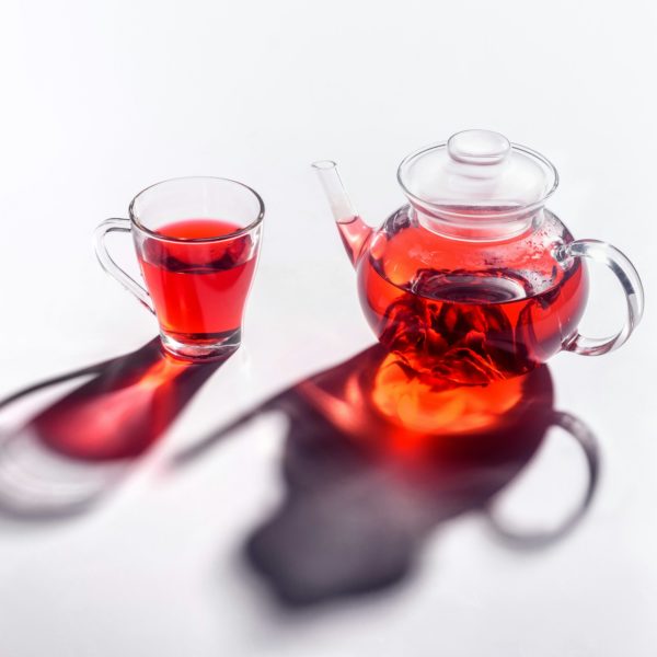 glass teapot and glass cup with hibiscus tea on tabletop